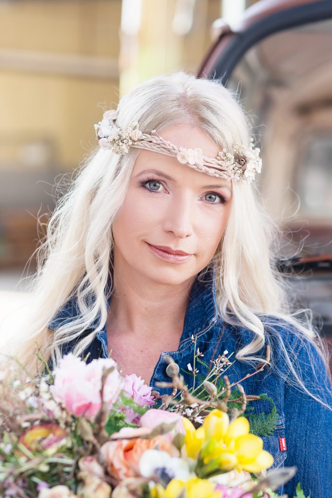 Braut mit langem blonden Haar und Jeansjacke und buntem Brautstrauß mit Frühlingsblumen